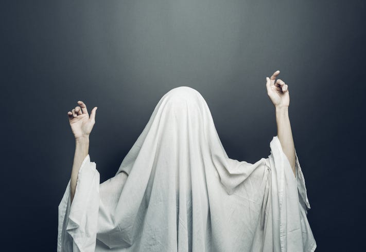Girl in costume Spooky white ghost with black eyes on a gray background. Halloween minimal concept