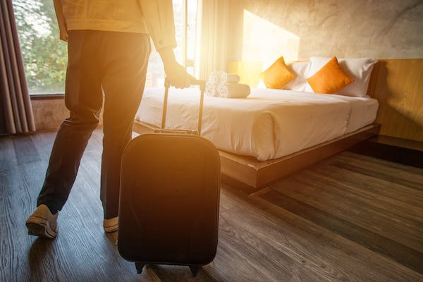 Woman rolling luggage into bedroom