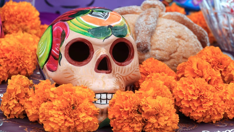 A sugar skull and pan de muerto are included on a Dia de los Muertos ofrenda.