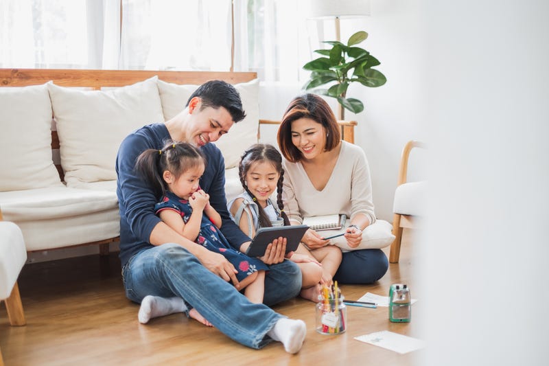 Parents and two daughters use a tablet device together