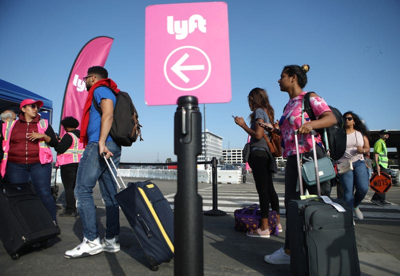 FILE - Arriving passengers wait to board Lyft vehicles at the new 'LAX-it' ride-hail passenger pickup lot at Los Angeles International Airport (LAX) on November 6, 2019 in Los Angeles.