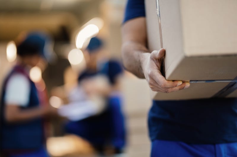 Close-up of a worker carrying cardboard box while making a delivery.