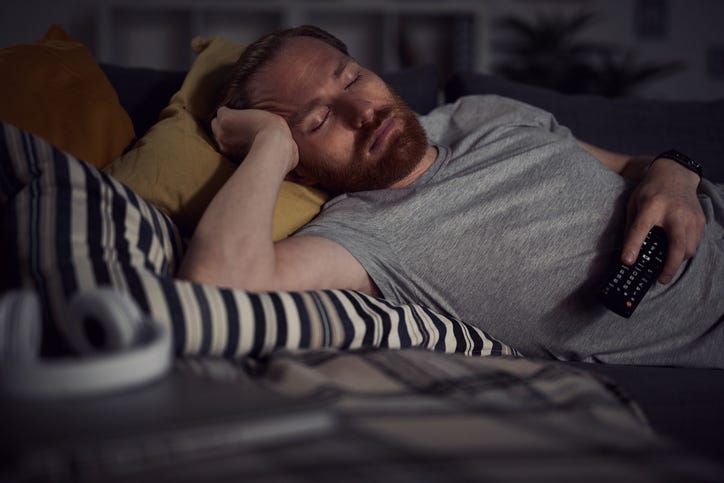 man sleeping in front of TV