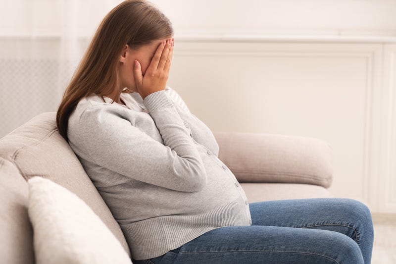 Pregnant woman covering her face with her hands