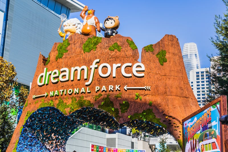 Rocky-façade entrance structure with Dreamforce National Park attached to it with some of the San Francisco skyline in the background.