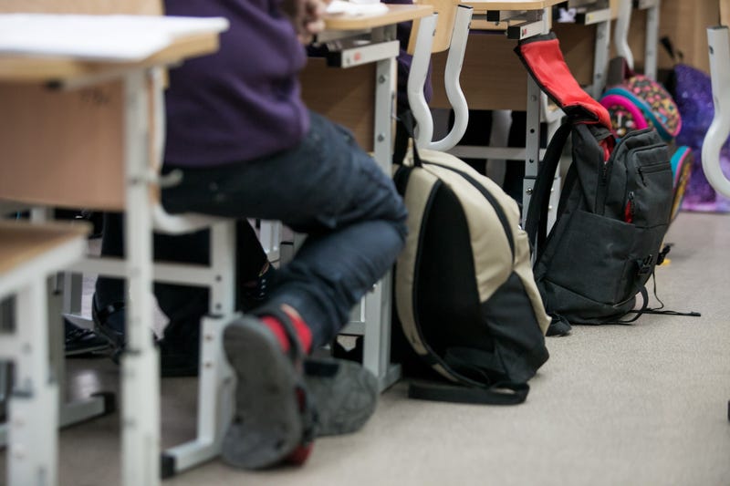 Backpacks next to students at classroom desks