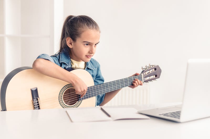 little girl taking guitar lesson online