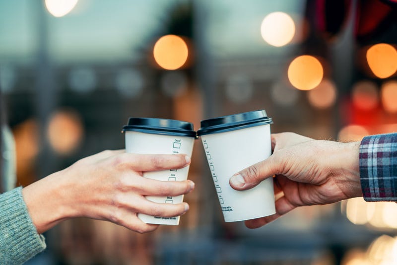 A couple is toasting with paper cup and drink coffee - stock photo