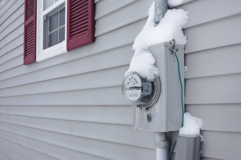 Snow on an electrical utility meter on house exterior siding.