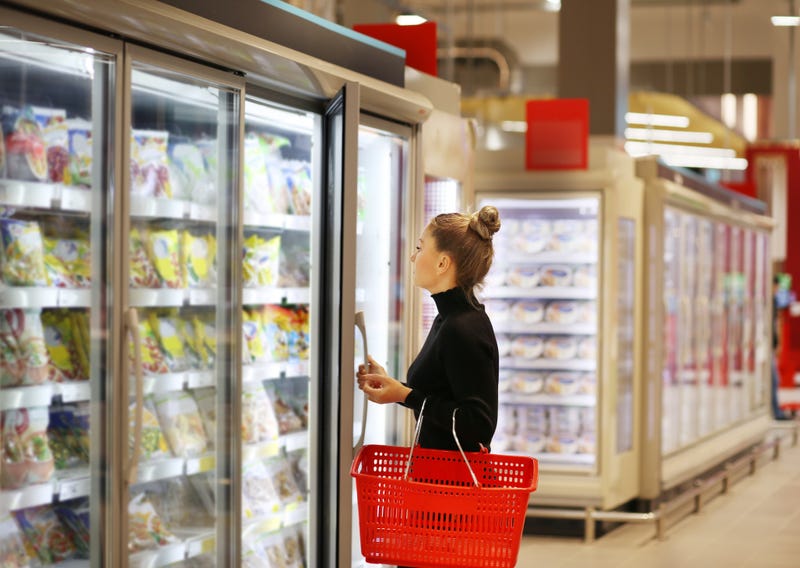 Woman choosing frozen food from a supermarket freezer.