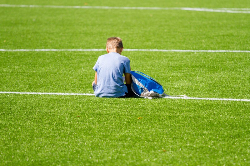 Sad kid sitting on soccer field