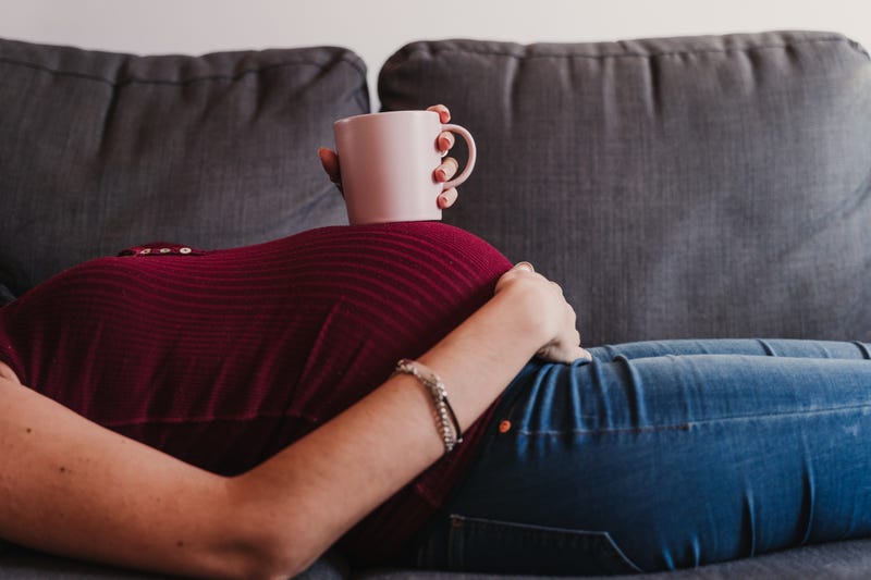 Young pregnant woman with a cup of coffee. 