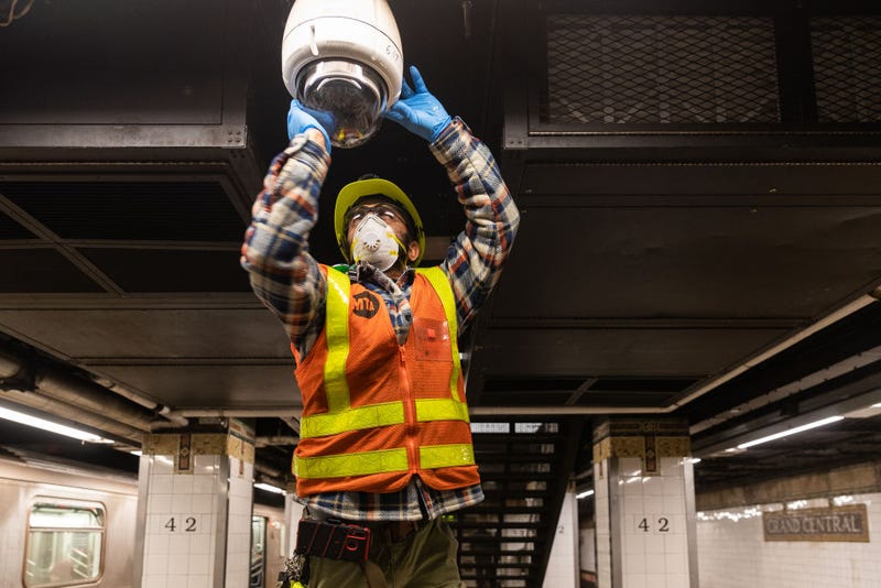 An MTA employee wearing a protective mask cleans a subway security camera at Grand Central Terminal on March 12, 2020 in New York City.
