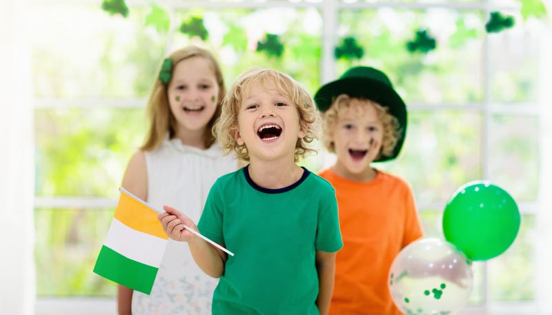 Family celebrating St. Patrick’s Day. Irish holiday, culture and tradition. Kids wear green leprechaun hat and beard with Ireland flag and clover leaf. Children having fun at St Patrick party.