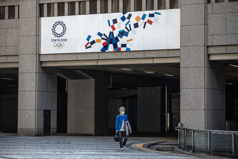 A woman walks beneath a Tokyo 2020 Olympics banner on March 19, 2020 in Tokyo, Japan.