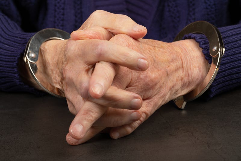 Elderly person in handcuffs. 