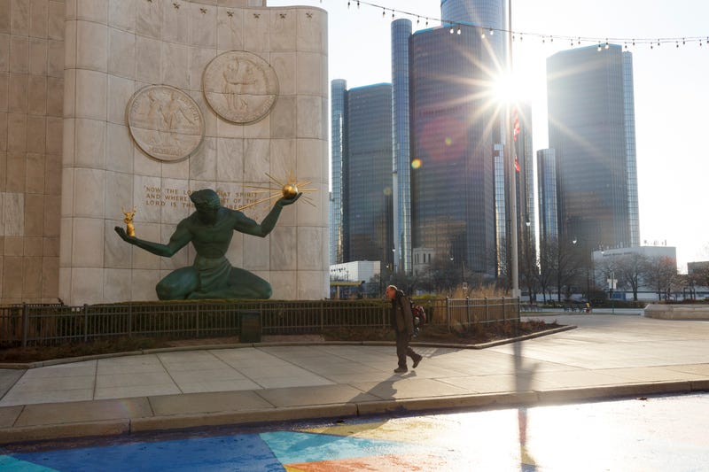 Man walks in front of the Spirit of Detroit