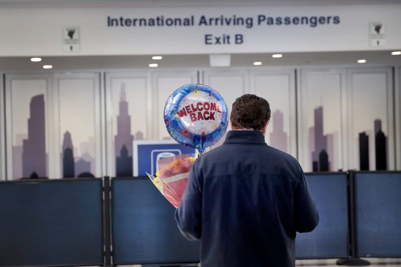 A person holds flowers and a balloon as they wait in O'Hare Airport's international terminal