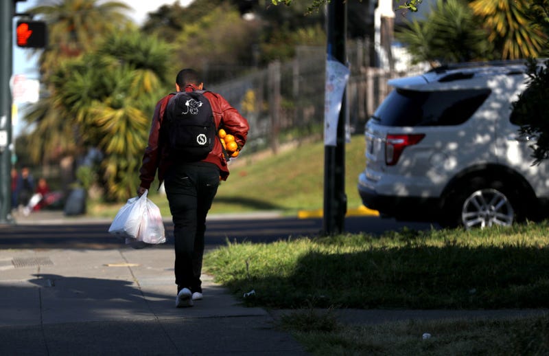 A man carries oranges and a bag of food that he received from the faculty at Garfield Elementary School on March 19, 2020 in Oakland, California.
