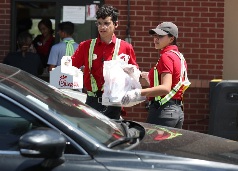 Workers at a Chick-fil-A deliver meals to customers in their vehicles at the drive-up window after the restaurant closed its indoor seating in an effort to curb the spread of the coronavirus pandemic on March 20, 2020 in Pembroke Pines, Florida.