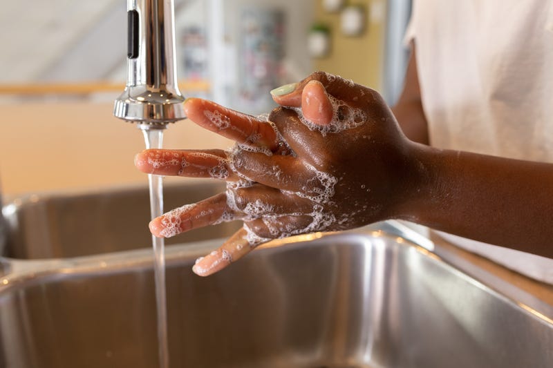 Someone washing hands at a faucet.