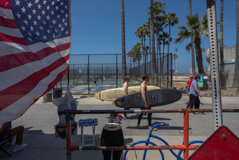 Surfers walk the boardwalk as holiday beach-goers head to Venice Beach on Memorial Day as coronavirus safety restrictions continue being relaxed in Los Angeles County and nationwide on May 24, 2020 in Los Angeles, California.