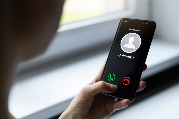A woman holding a mobile phone with an incoming call from an unknown caller.