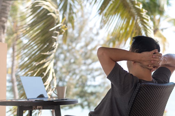 Man relaxes outdoors sitting in front of computer