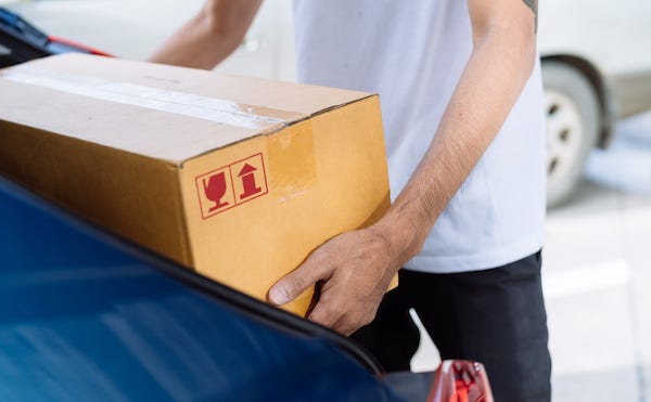 Man placing cardboard box in trunk