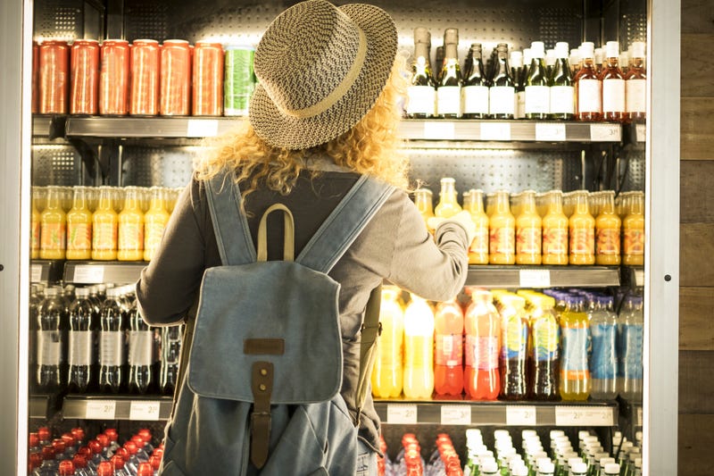 ravel woman viewed from back choosing beverage in a fresh fridge
