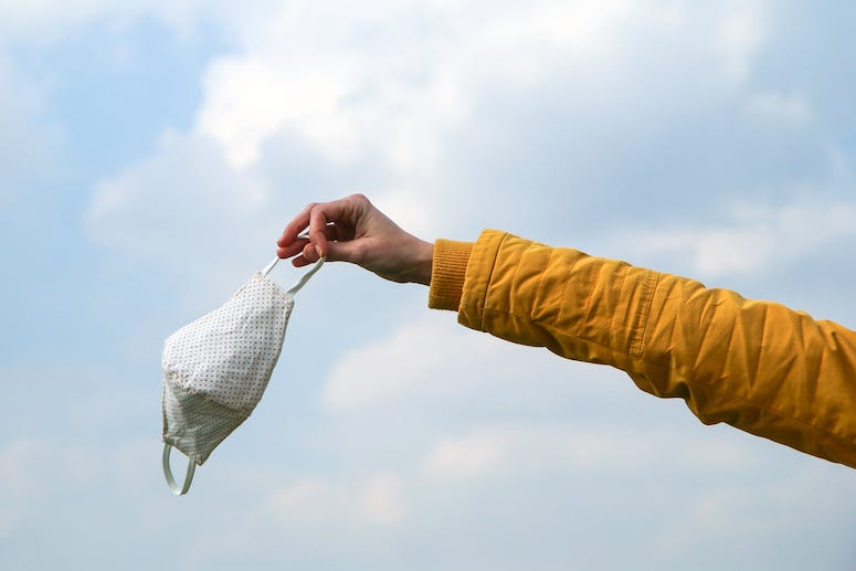 Woman holding face mask, Blue Sky