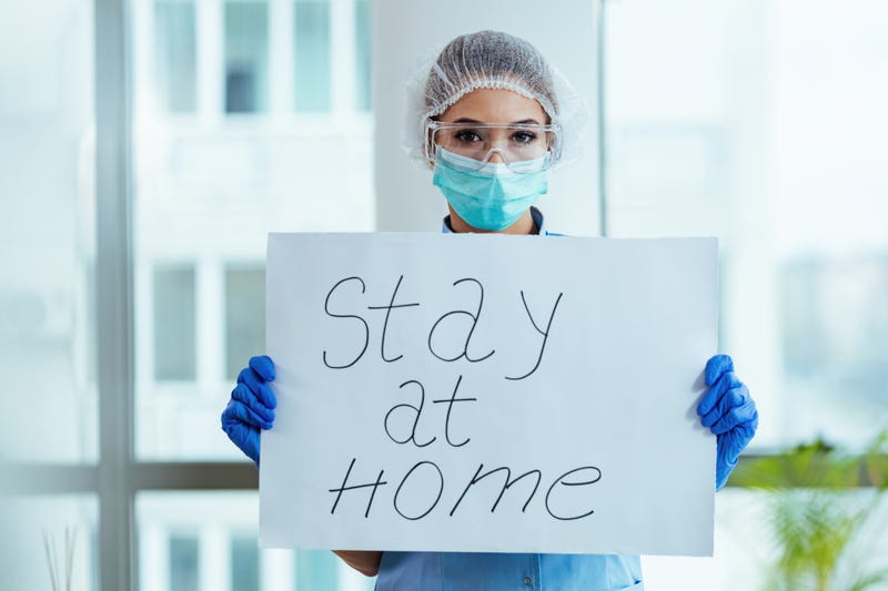 Female doctor holding placard with stay at home message as appeal for social distancing during a coronavirus epidemic.
