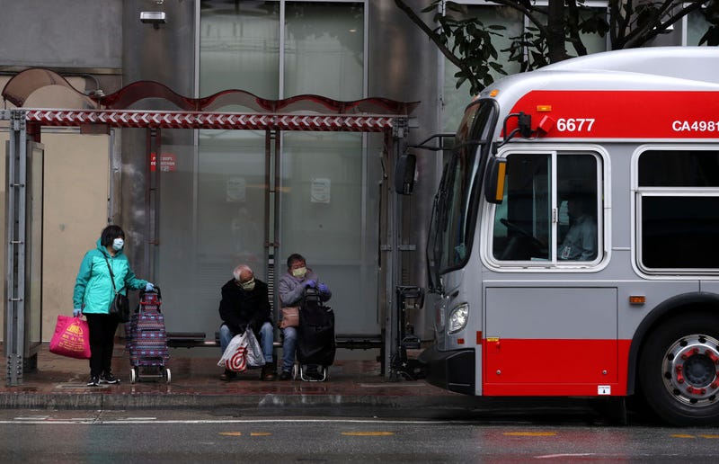 People wear masks as they wait in a bus shelter for a San Francisco MUNI bus during the coronavirus (COVID-19) pandemic on April 06, 2020 in San Francisco, California.