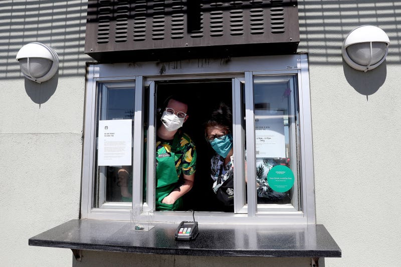 Starbucks employees wear a mask while working the drive-thru window