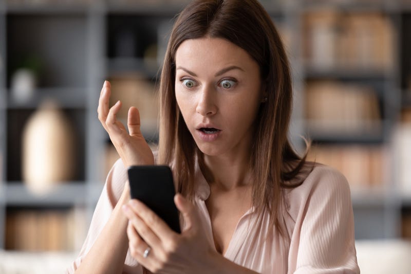 Shocked young woman looking at her smartphone. 