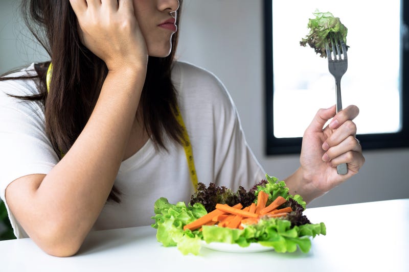 Unhappy women is on dieting time looking at vegetable on the fork