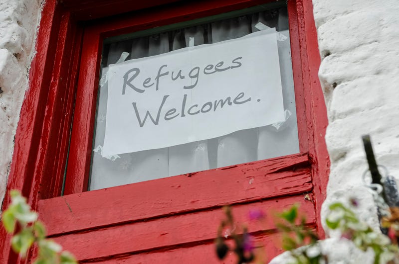 Handwritten "Refugees Welcome" sign hangs in window