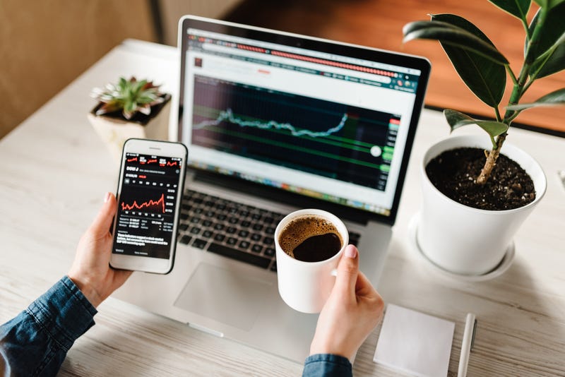 Person looking at investment information on laptop and mobile phone.
