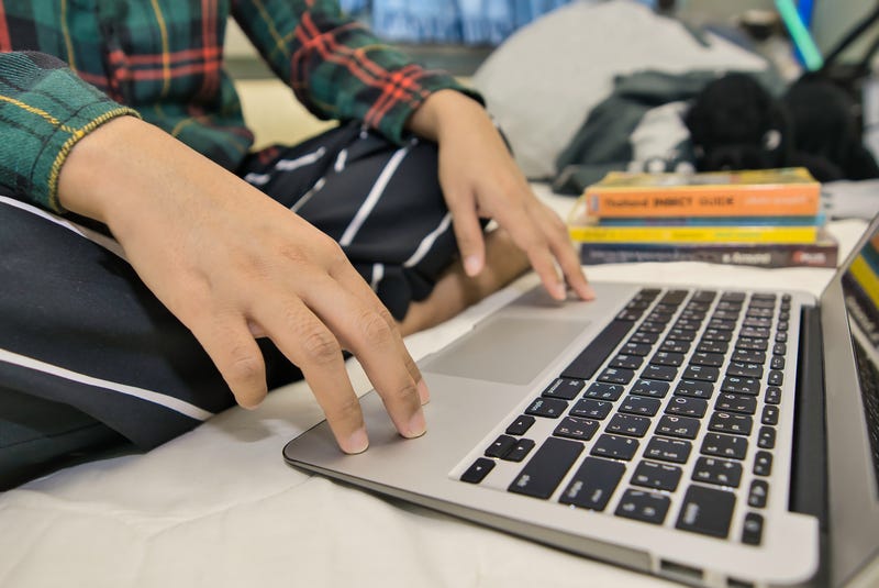 student working on laptop in bed