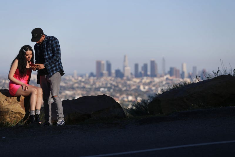 People take photos with downtown visible in the distance in the midst of the coronavirus pandemic on April 15, 2020 in Los Angeles, California. Environmental Protection Agency (EPA) data from March shows that Los Angeles had its longest stretch of air quality rated as "good" since 1995 as Safer-at-Home orders were issued in response to the spread of COVID-19. (Photo by Mario Tama/Getty Images)