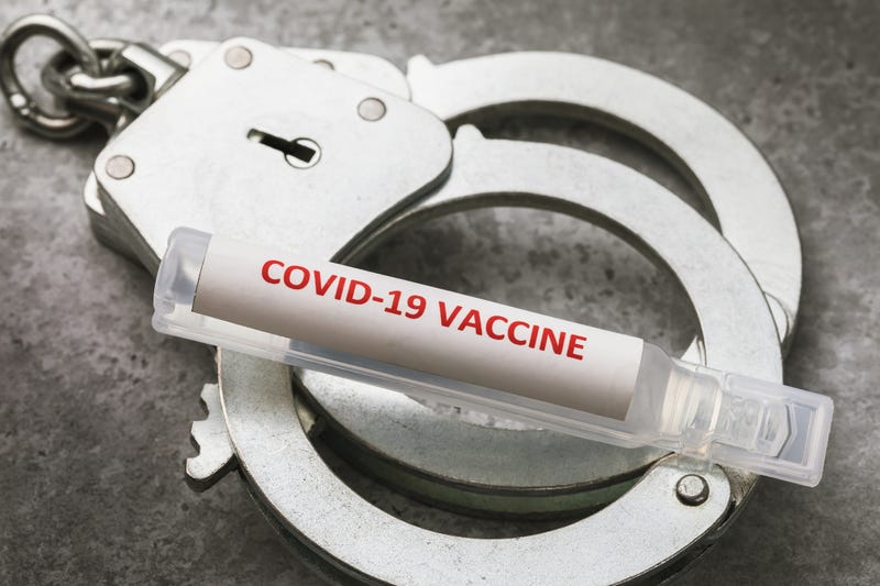 An ampoule with a covid-19 pandemic vaccine and handcuffs