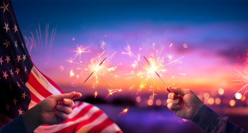 USA Celebration With Hands Holding Sparklers And American Flag At Sunset With Fireworks