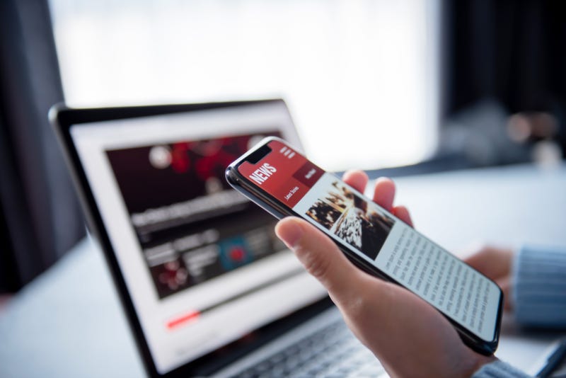 Online news on a smartphone and laptop.