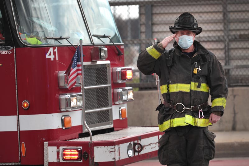 Firefighters salute as a funeral procession carrying the remains of Firefighter Edward Singleton, a 33 year veteran of the Chicago Fire Department, passes by on the way to the cemetery on April 22, 2020 in Chicago, Illinois.