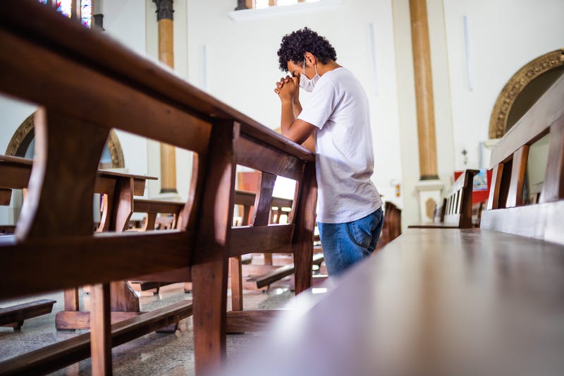 Man praying while wearing a mask.