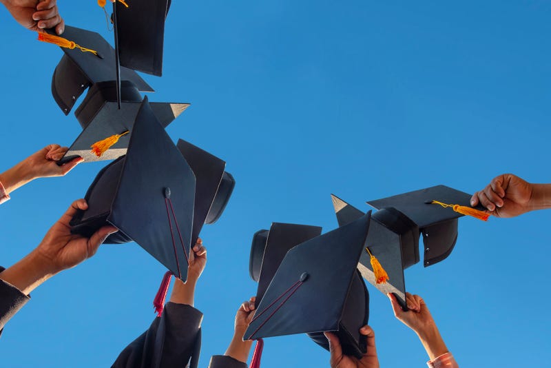 e students holding a shot of graduation cap by their hand in a bright sky during ceremony success graduates at the University