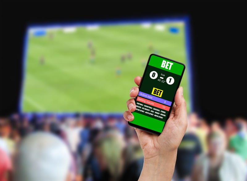 Close-up on man holding a cell phone while winning an online bet on a football game at bar