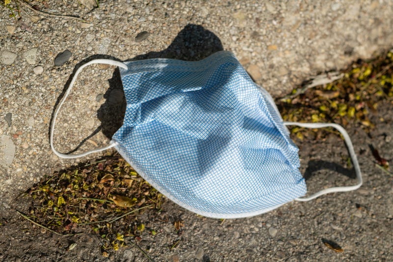 A discarded face covering lies on the ground