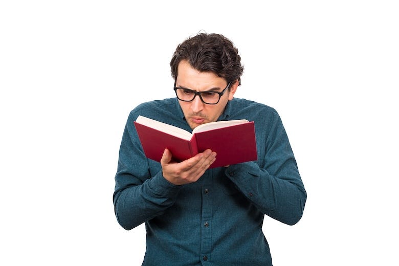 Man wearing glasses confused reading a book