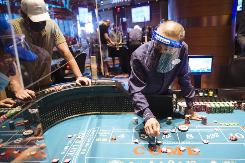 An employee wearing a protective mask and face shield speaks to a visitor at a craps table at the Ocean Casino Resort in Atlantic City.